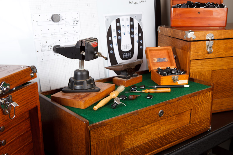 The workshop bench — vise, anvil, the etched 60 badge plate, and vintage tools