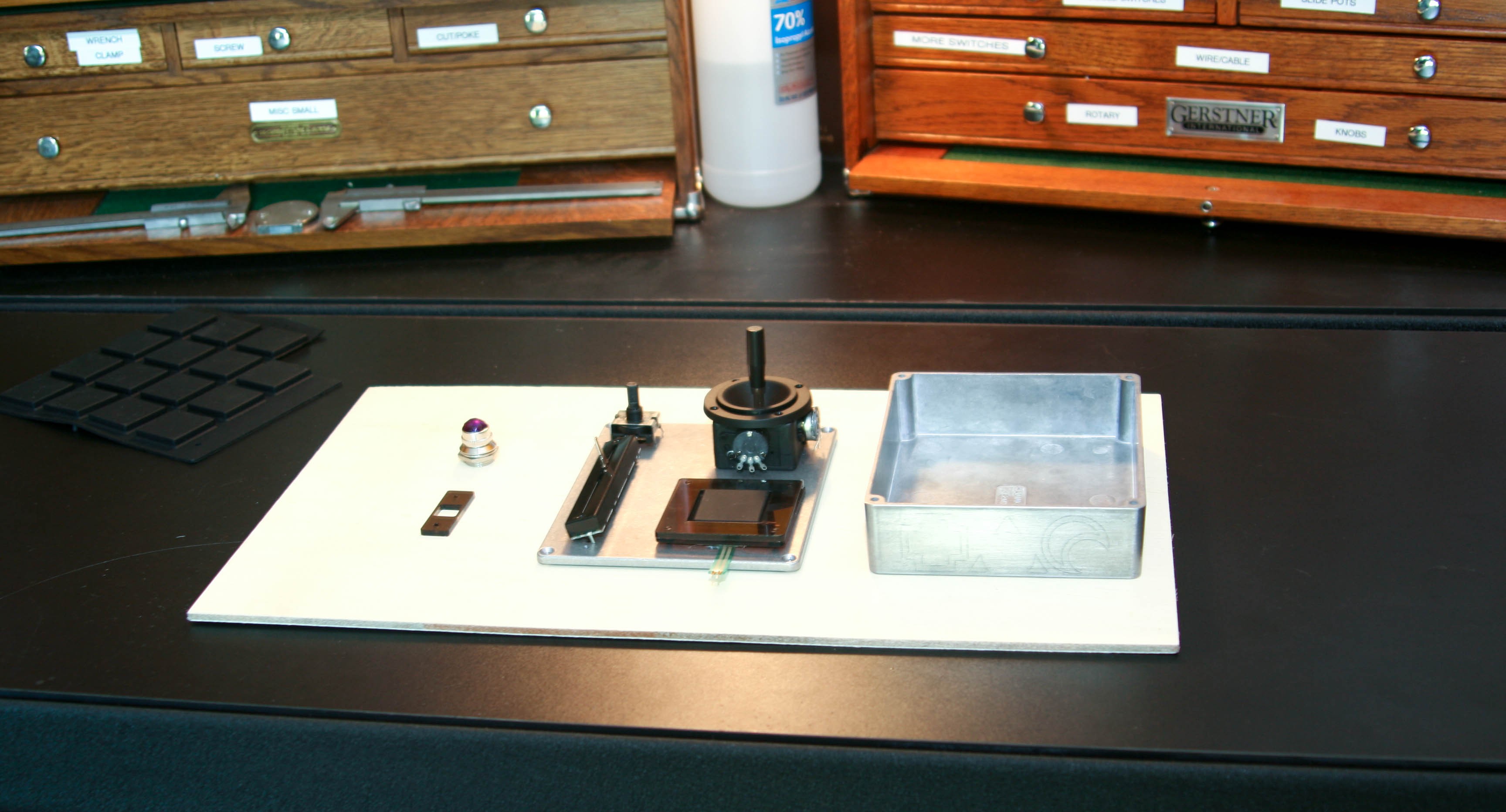 Controller components — LED, slide pot, joystick and enclosure — laid out on a white board in front of Gerstner tool chests