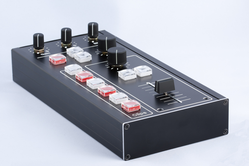A compact black aluminum controller with illuminated red and white buttons, knobs and a fader on a clean white sweep