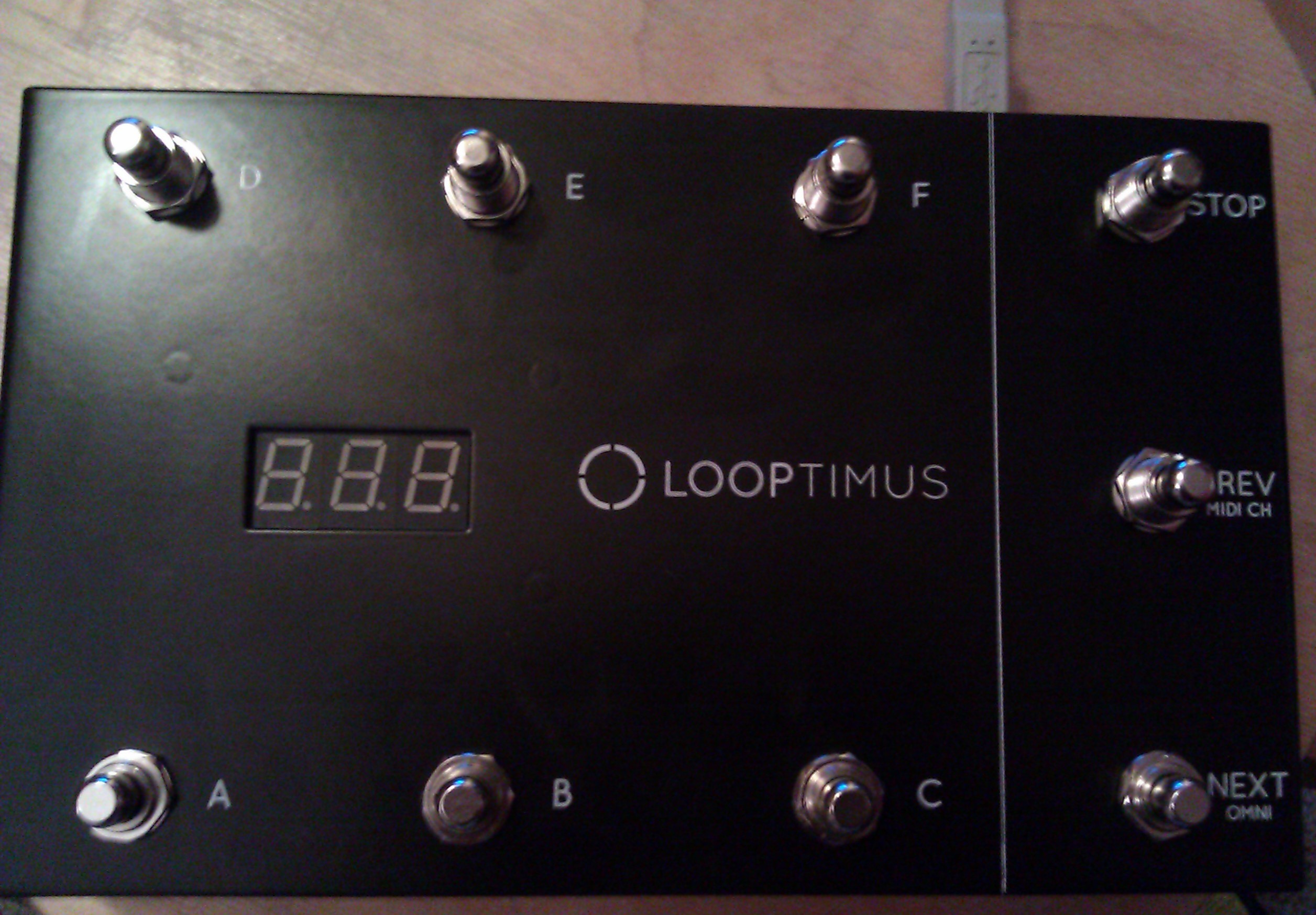 The LOOPTIMUS black foot controller with stomp switches labelled A through F, STOP, PREV and NEXT, and a seven-segment display